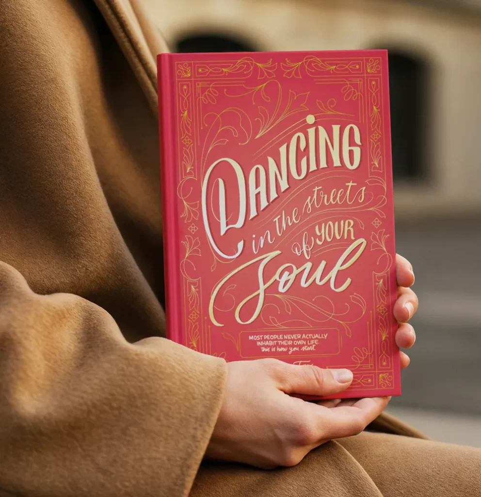 Mano sosteniendo el libro «Dancing in the Streets of Your Soul» con portada de lettering diseñada por Ingrid Luque